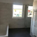 Baezimmer mit Badewanne, Dusche und Sprossenheizkörper